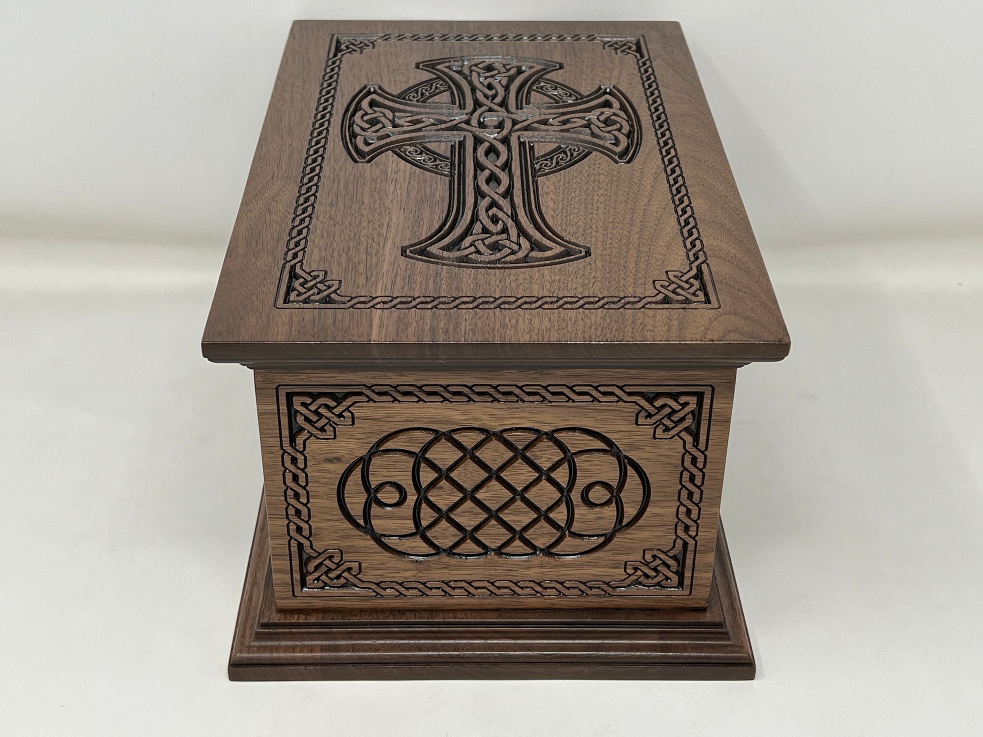 Celtic Cross and Weave Urn viewed from the short side with the top in view as well. The cross is seen on the top and the short side has the celtic weave carving, both surrounded by the celtic weave boarder.