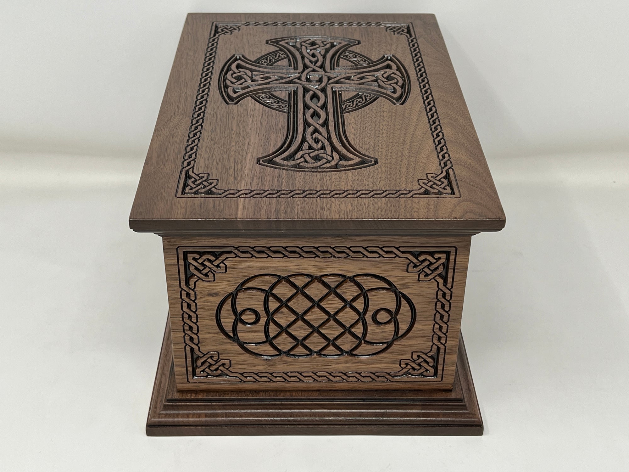 Celtic Cross and Weave Urn viewed from the short side with the top in view as well. The cross is seen on the top and the short side has the celtic weave carving, both surrounded by the celtic weave boarder.