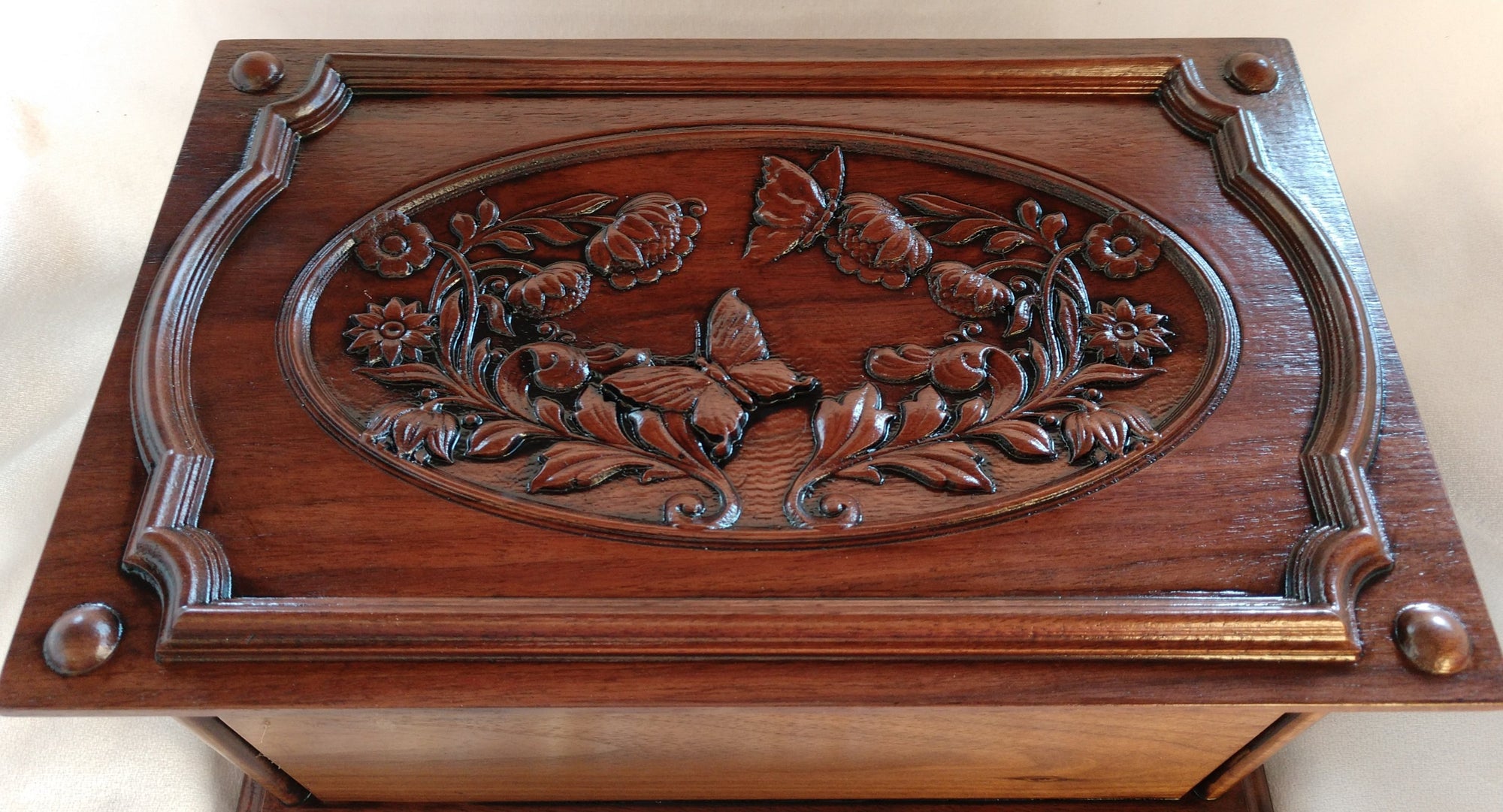 The top has carved images of butterflies and flowers surrounded by an ornate border • Beaded corners with molded edges Human ash urn for sale - elegant and dignified urn for storing cremated remains.